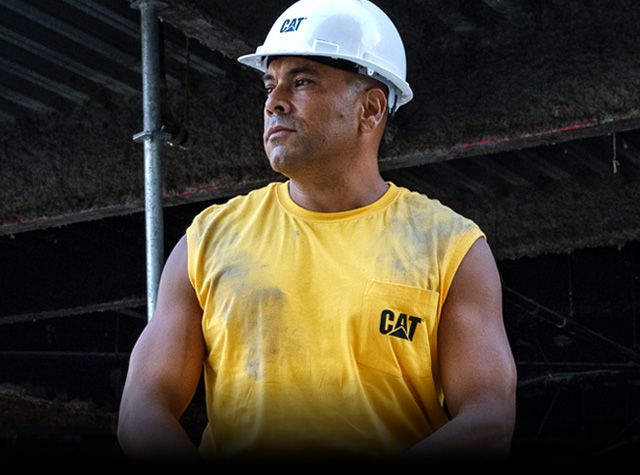 Man under scaffolding wearing a hard hat and yythkg